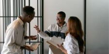 Three colleagues having a lively discussion, holding notebooks.