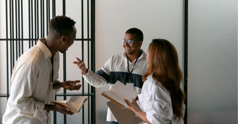 Three colleagues having a lively discussion, holding notebooks.