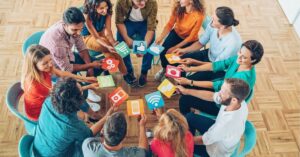 A group of people sitting in a circle, each holding social media icon cards.