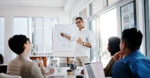 Team engaged in a presentation, with a leader explaining strategy on a flip chart.