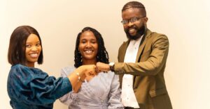 Three colleagues smiling and fist-bumping in celebration.