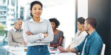 Confident professional standing in front of colleagues during a meeting.