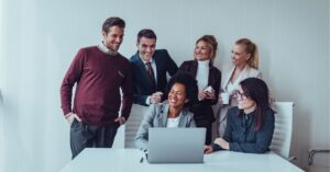 Team of professionals gathered around a laptop, smiling and engaged.