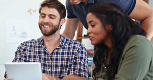 Team collaborating around a tablet, smiling and discussing ideas.