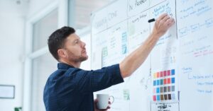 Person writing notes on a notepad beside a laptop, symbolizing planning and creativity.