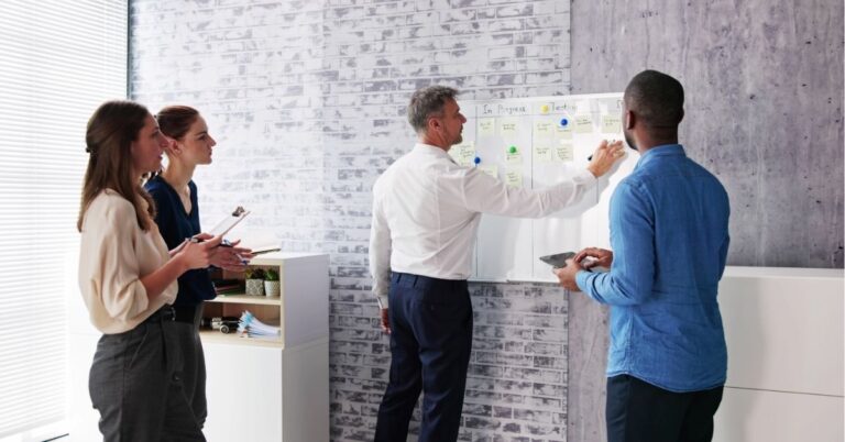 Team collaborating at a whiteboard with sticky notes.