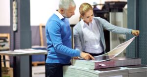 Two people reviewing a large print document in a printing facility.