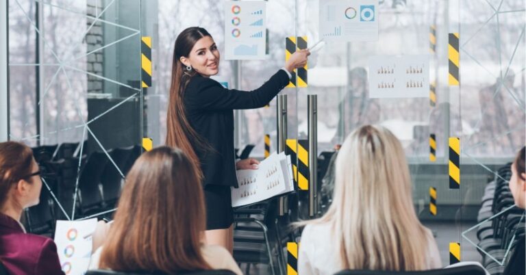 Businesswoman presenting charts to a group in a modern office.