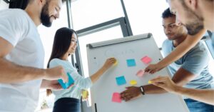 Team collaborating with sticky notes on a whiteboard, setting goals.