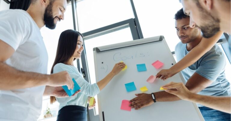 Team collaborating with sticky notes on a whiteboard, setting goals.
