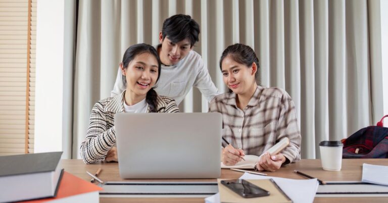 Three young entrepreneurs collaborating around a laptop in a casual office setting
