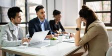 Team in a meeting around a table with laptops and documents.