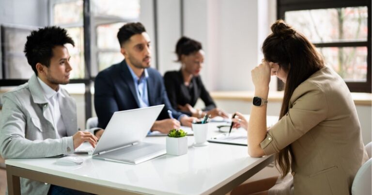 Team in a meeting around a table with laptops and documents.