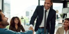 Business professionals shaking hands in a meeting room, smiling.