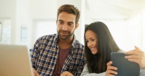 Father and daughter smiling while looking at a laptop together.