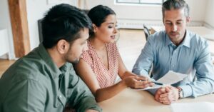 Three colleagues reviewing documents in a meeting.