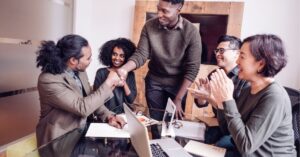 Team of professionals celebrating a successful meeting with smiles and handshakes.