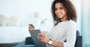 Notepad and pen beside a laptop on a desk.