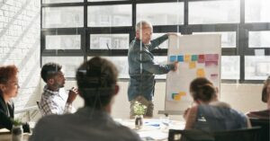 Person giving a presentation with sticky notes on a board in a meeting room.