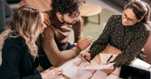 Three colleagues discussing documents at a table.