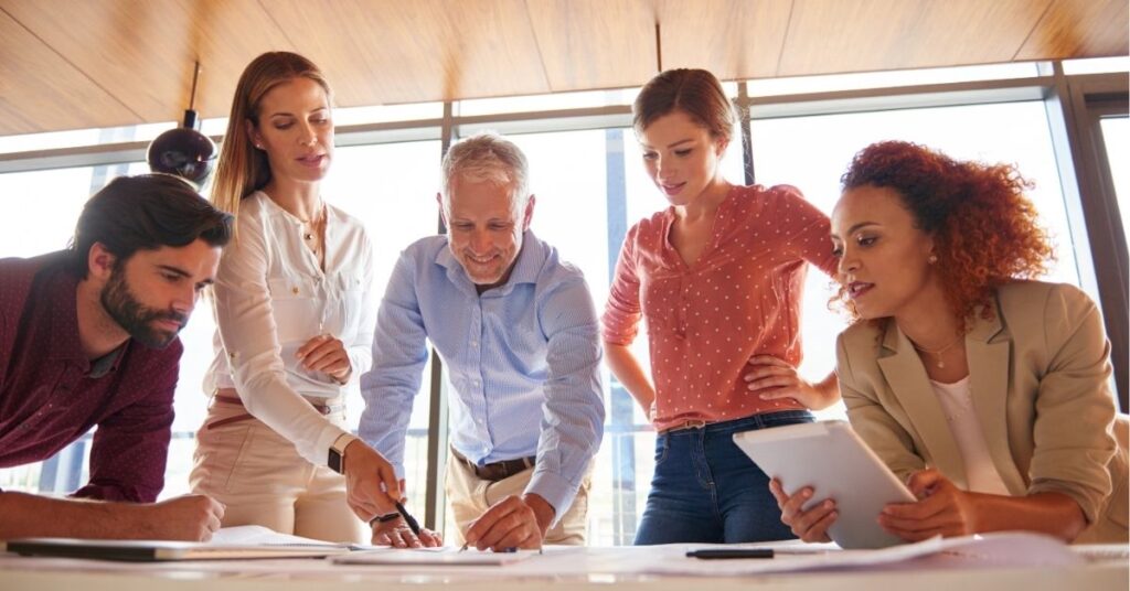 Team collaborating on a project, reviewing documents and using a tablet.