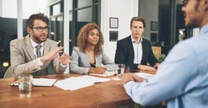 Business team in a meeting, engaged in a discussion around a table.