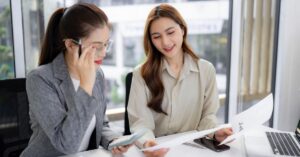 Two coworkers reviewing a printed report and phone data, likely during a gap analysis meeting.