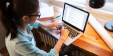 Person writing a blog post on a laptop at a desk.