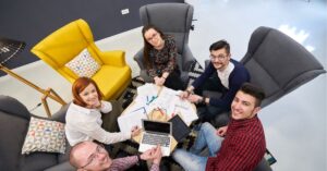 Team of young professionals collaborating around a table with laptops and papers.