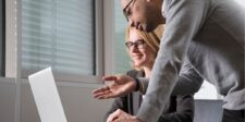 Two colleagues collaborating at a laptop in an office setting.
