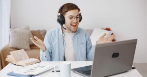 Man wearing headphones, smiling during a video call on a laptop.