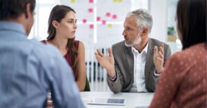 Diverse group engaged in a serious discussion around a conference table.