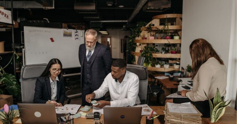 Team collaborating in a modern office with plants and a whiteboard.