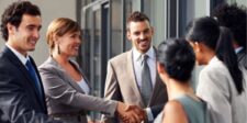 How To Create Raving Fans in Business That Last Group of professionals networking and shaking hands outside a modern office building.