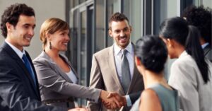 Group of professionals networking and shaking hands outside a modern office building.