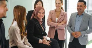 A diverse group of professionals smiling and chatting in a bright office setting.
