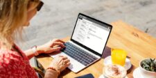 EML to PDF Conversion: Practical Methods for Email Preservation Woman sitting at an outdoor table using a laptop with her email inbox open, next to orange juice, coffee, and a small plant.