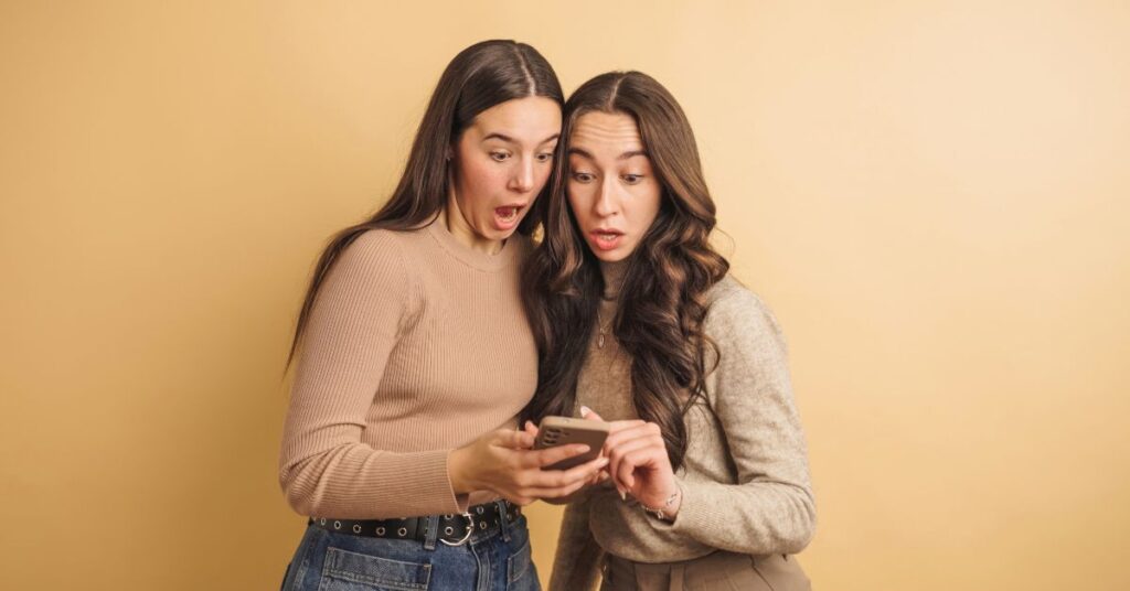 Two women looking surprised at a smartphone.
