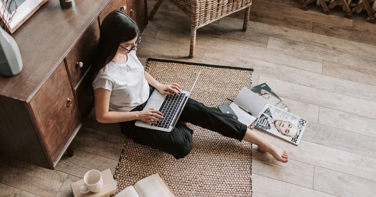 Person sitting on a wooden dock with a laptop at sunset, symbolizing the freedom of starting a blog and earning online.