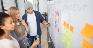 Team reviewing a website layout on a whiteboard with sticky notes during a design workshop.