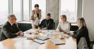Team meeting in a modern office reviewing charts and reports around a conference table.