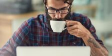 Person working on a laptop while drinking coffee.
