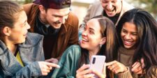 Group of friends laughing while looking at a smartphone