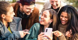 Group of friends laughing while looking at a smartphone