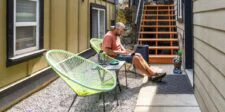 Remote Work Statistics: What’s True Right Now (And What People Get Wrong) A person working on a laptop on an outdoor patio with a suitcase nearby, illustrating remote work.