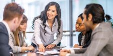 Business team in a meeting as a woman points to a document on the table while others listen.
