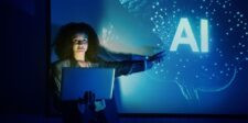 Google AI Mode Will Become the Default: 11 Predictions for Search Woman holding a laptop and gesturing toward a glowing AI display on a blue presentation screen with a digital brain graphic in the background.
