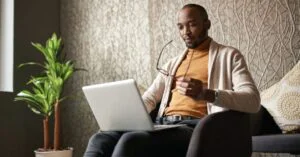 Man sitting in a chair and looking at a laptop, used as the featured image for a free outline generator article.