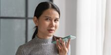 Woman speaking into a smartphone indoors, illustrating how people use AI on their phones today