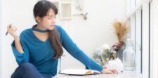 Woman sitting by a window and writing in a notebook, used as the featured image for a free word counter article.